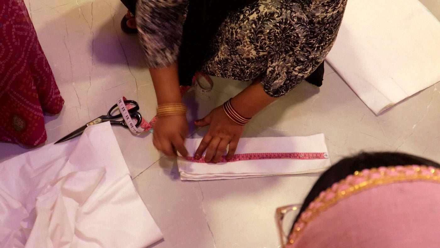 Hands measuring fabric during tailoring training